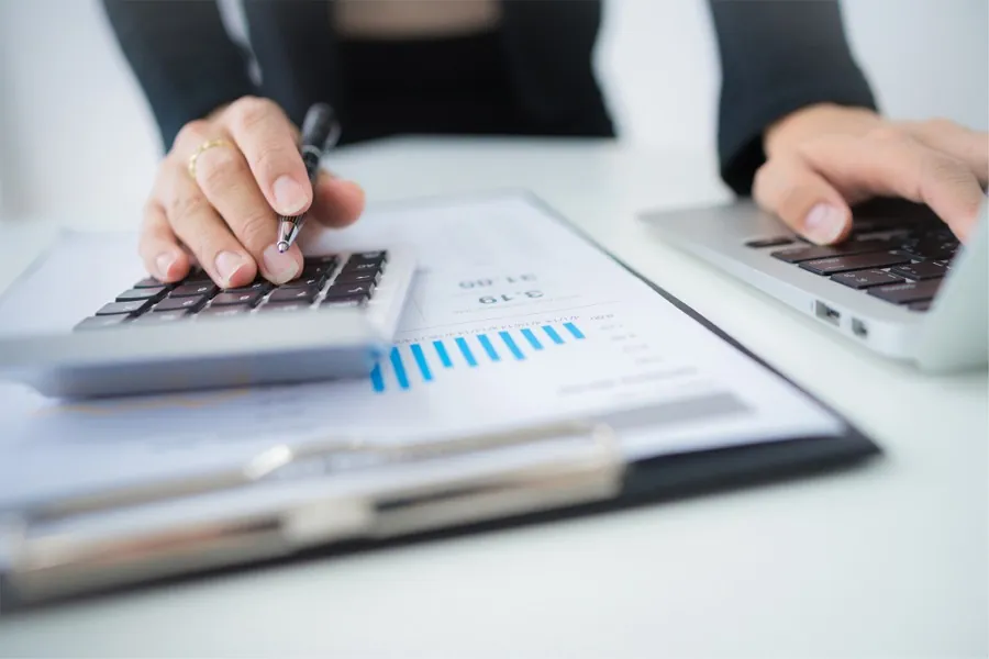 Hands working through a quote on a calculator beside a printed cost breakdown