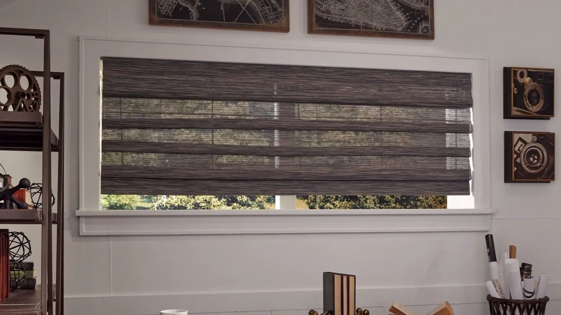 A woven wood Roman shade half lowered over a window in a styled room